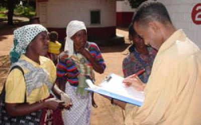 Man with a clipboard talking to woman in a village